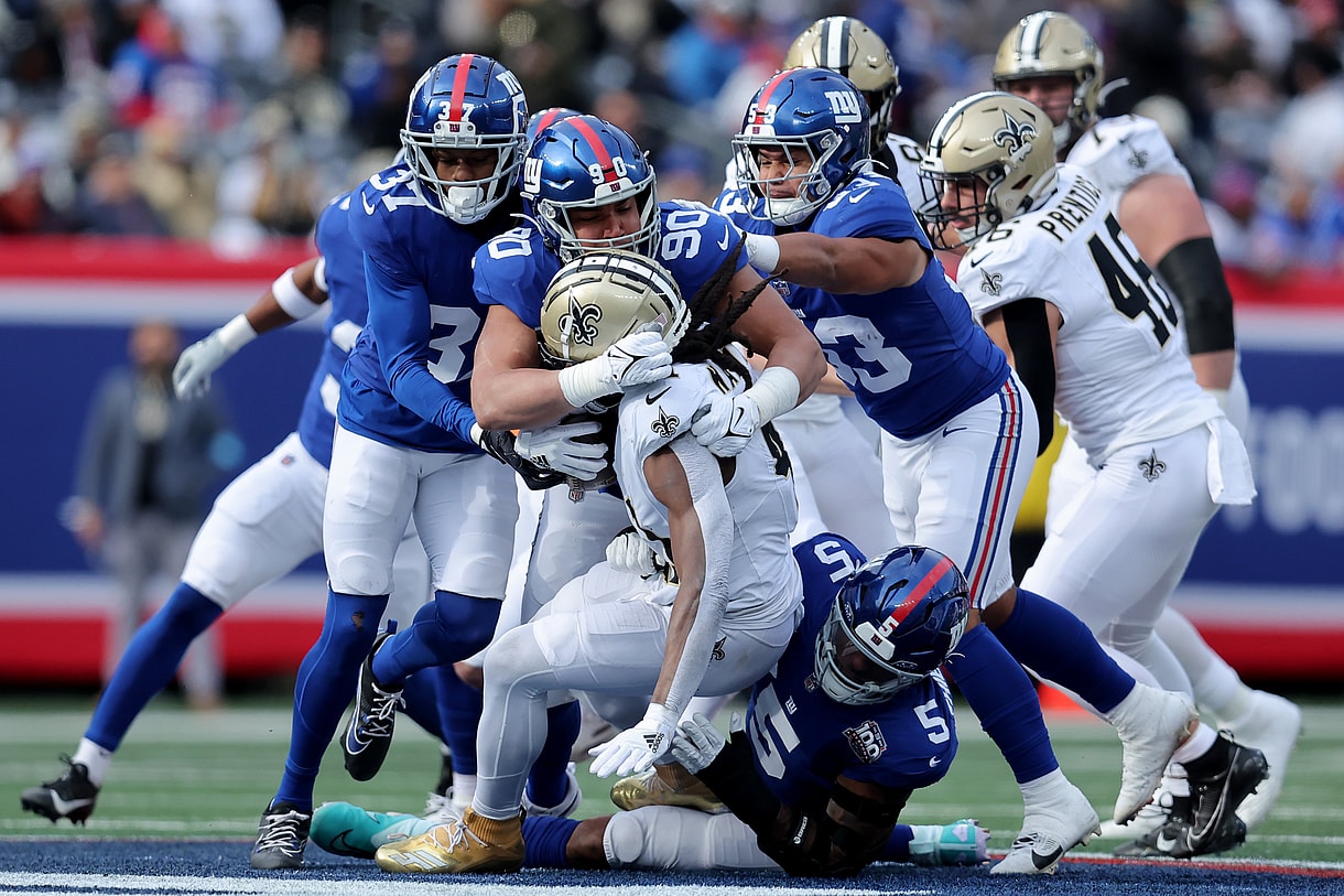 Dec 8, 2024; East Rutherford, New Jersey, USA; New Orleans Saints running back Alvin Kamara (41) is tackled by New York Giants cornerback Tre Hawkins III (37) and defensive end Elijah Garcia (90) and linebacker Darius Muasau (53) and linebacker Kayvon Thibodeaux (5) during the first quarter at MetLife Stadium. Mandatory Credit: Brad Penner-Imagn Images