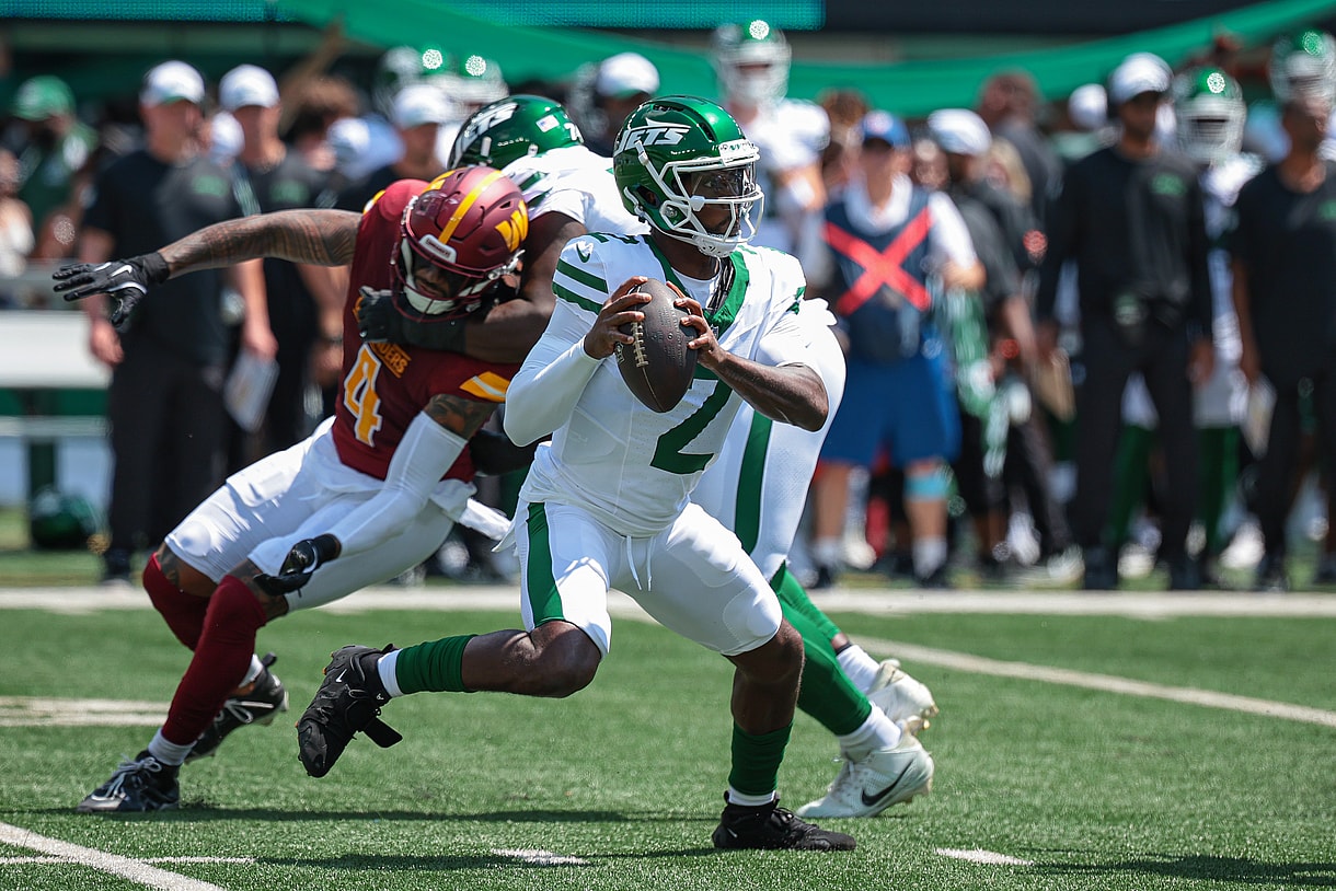 Aug 10, 2024; East Rutherford, New Jersey, USA; New York Jets quarterback Tyrod Taylor (2) looks to pass as Washington Commanders linebacker Frankie Luvu (4) defends during the first quarter at MetLife Stadium. Mandatory Credit: Vincent Carchietta-Imagn Images
