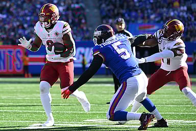 Washington Commanders running back Brian Robinson Jr. (8) runs as New York Giants defensive end Kayvon Thibodeaux (5) defends during the first half at MetLife Stadium
