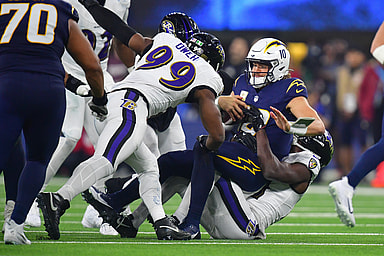 Nov 25, 2024; Inglewood, California, USA; Los Angeles Chargers quarterback Justin Herbert (10) is sacked by Baltimore Ravens cornerback Brandon Stephens (21) and linebacker Odafe Oweh (99) during the second half at SoFi Stadium. Mandatory Credit: Gary A. Vasquez-Imagn Images