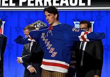 Jun 28, 2023; Nashville, Tennessee, USA; New York Rangers draft pick Gabriel Perreault puts on his sweater after being selected with the twenty third pick in round one of the 2023 NHL Draft at Bridgestone Arena. Mandatory Credit: Christopher Hanewinckel-USA TODAY Sports