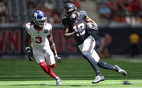 Aug 17, 2024; Houston, Texas, USA; Houston Texans wide receiver Nico Collins (12) runs with the ball after a reception as New York Giants cornerback Deonte Banks (3) defends during the first quarter at NRG Stadium. Mandatory Credit: Troy Taormina-USA TODAY Sports