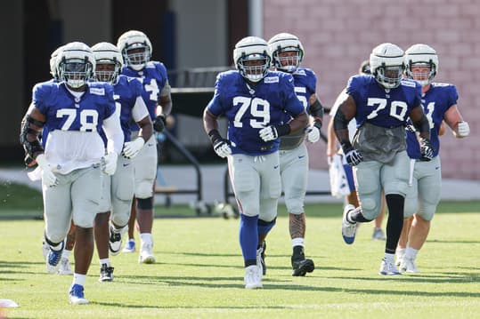 New York Giants offensive tackle Andrew Thomas (78) and offensive tackle Tyre Phillips (79) and offensive tackle Korey Cunningham (70) jog on the field with teammates during training camp at the Quest Diagnostics Training Facility
