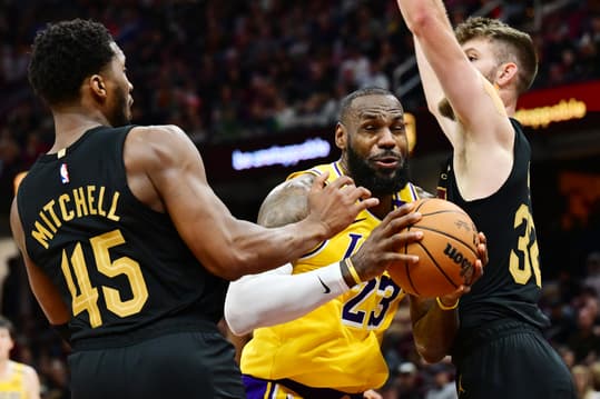 Oct 30, 2024; Cleveland, Ohio, USA; Los Angeles Lakers forward LeBron James (23) drives to the basket between Cleveland Cavaliers guard Donovan Mitchell (45) and forward Dean Wade (32) during the second half at Rocket Mortgage FieldHouse. Mandatory Credit: Ken Blaze-Imagn Images