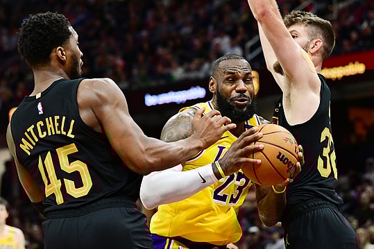 Oct 30, 2024; Cleveland, Ohio, USA; Los Angeles Lakers forward LeBron James (23) drives to the basket between Cleveland Cavaliers guard Donovan Mitchell (45) and forward Dean Wade (32) during the second half at Rocket Mortgage FieldHouse. Mandatory Credit: Ken Blaze-Imagn Images
