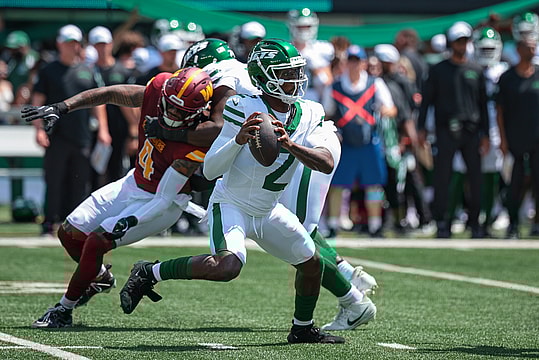 Aug 10, 2024; East Rutherford, New Jersey, USA; New York Jets quarterback Tyrod Taylor (2) looks to pass as Washington Commanders linebacker Frankie Luvu (4) defends during the first quarter at MetLife Stadium. Mandatory Credit: Vincent Carchietta-Imagn Images