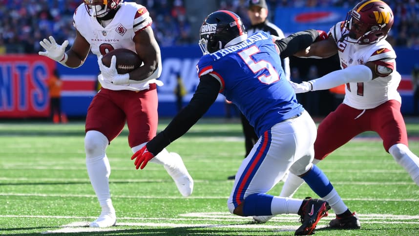 Washington Commanders running back Brian Robinson Jr. (8) runs as New York Giants defensive end Kayvon Thibodeaux (5) defends during the first half at MetLife Stadium