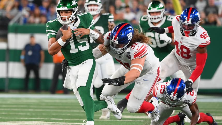 Aug 24, 2024; East Rutherford, New Jersey, USA; New York Jets quarterback Adrain Martinez (15) runs with the ball past New York Giants defensive tackle Casey Rogers (91) during the first half at MetLife Stadium. Mandatory Credit: Rich Barnes-Imagn Images