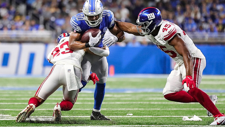 Detroit Lions running back Devine Ozigbo (30) runs against New York Giants linebacker Habakkuk Baldonado (45) and New York Giants safety Alex Cook (23) during the second half of a preseason game at Ford Field in Detroit