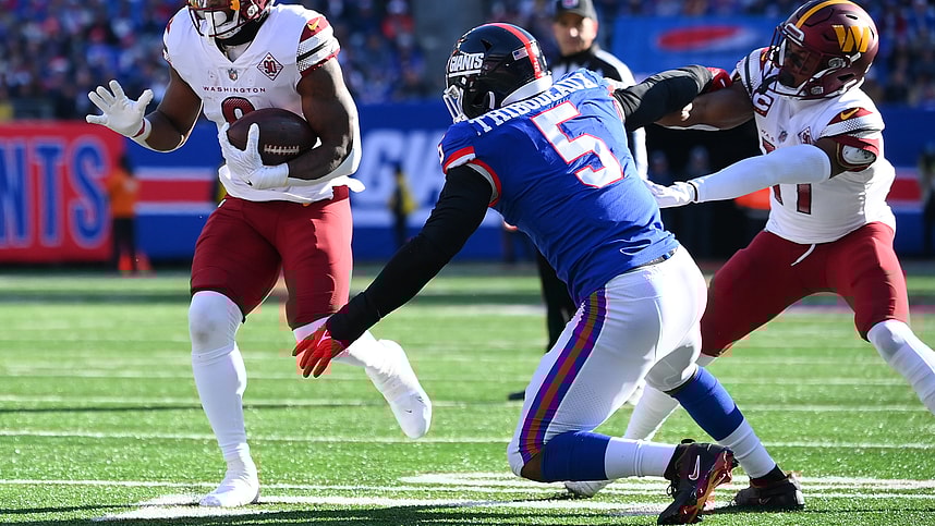Washington Commanders running back Brian Robinson Jr. (8) runs as New York Giants defensive end Kayvon Thibodeaux (5) defends during the first half at MetLife Stadium