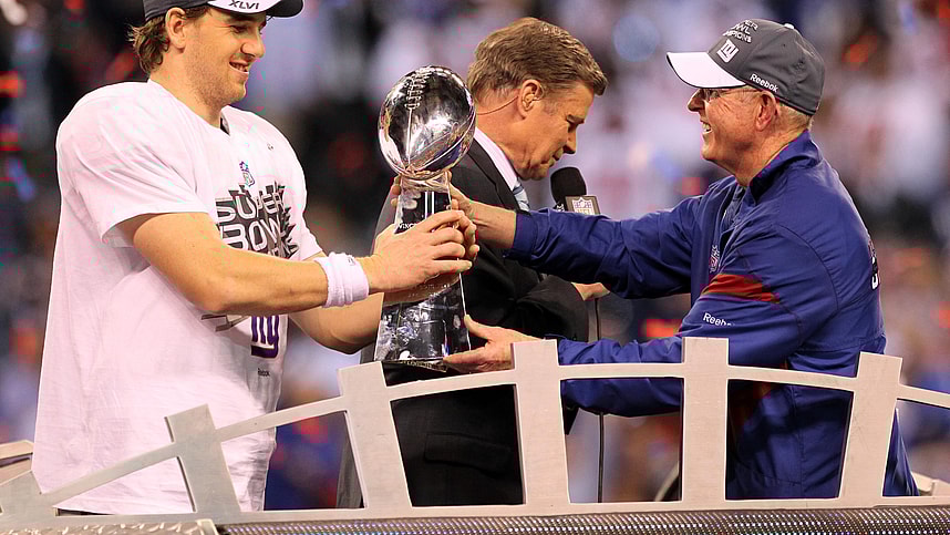 New York Giants head coach Tom Coughlin (right) hands the Vince Lombardi Trophy to quarterback Eli Manning (left) after Super Bowl XLVI against the New England Patriots at Lucas Oil Stadium