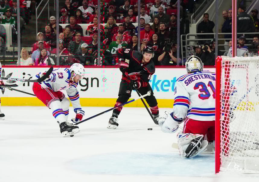 May 9, 2024; Raleigh, North Carolina, USA; Carolina Hurricanes center Jake Guentzel (59) sends the puck between New York Rangers defenseman Adam Fox (23) and goaltender Igor Shesterkin (31) during the first period in game three of the second round of the 2024 Stanley Cup Playoffs at PNC Arena. Mandatory Credit: James Guillory-USA TODAY Sports