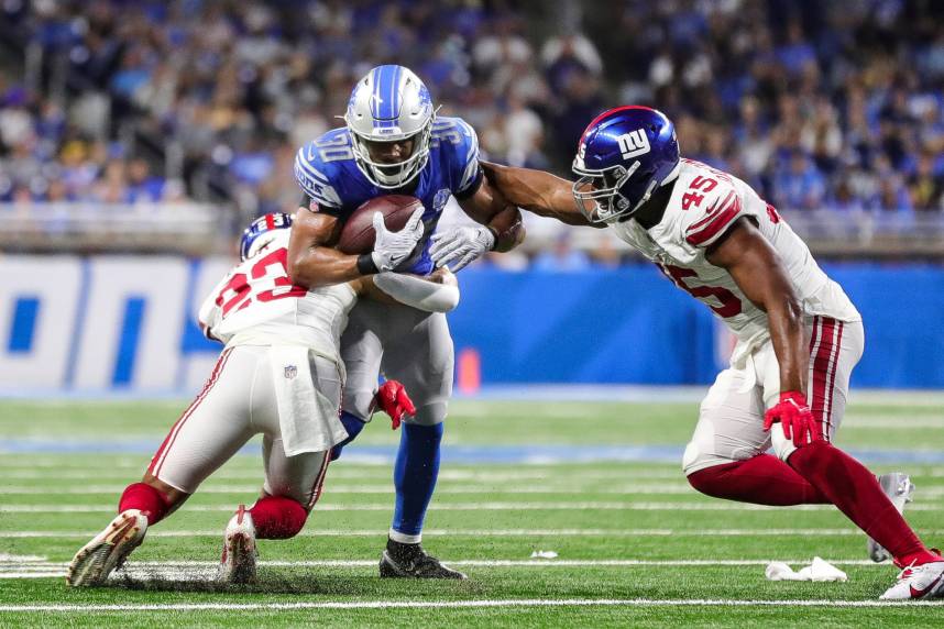 Detroit Lions running back Devine Ozigbo (30) runs against New York Giants linebacker Habakkuk Baldonado (45) and New York Giants safety Alex Cook (23) during the second half of a preseason game at Ford Field in Detroit
