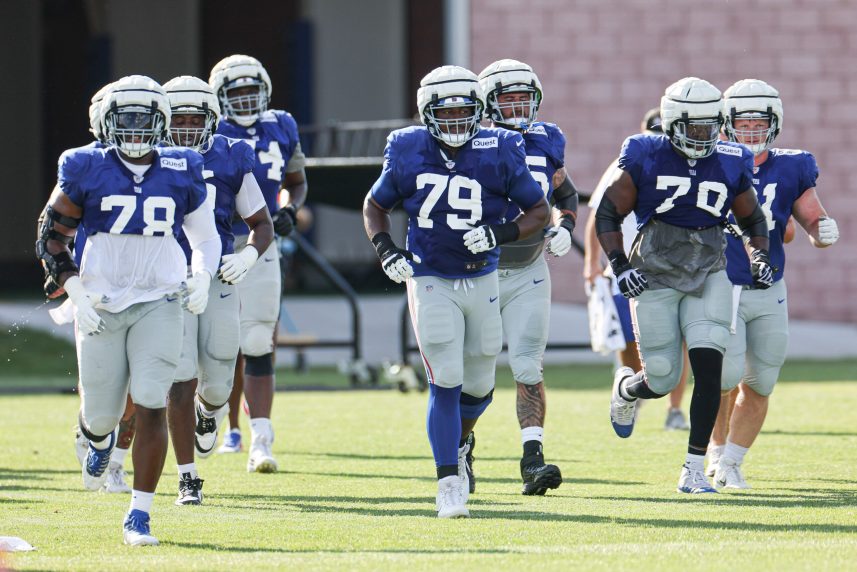 New York Giants offensive tackle Andrew Thomas (78) and offensive tackle Tyre Phillips (79) and offensive tackle Korey Cunningham (70) jog on the field with teammates during training camp at the Quest Diagnostics Training Facility