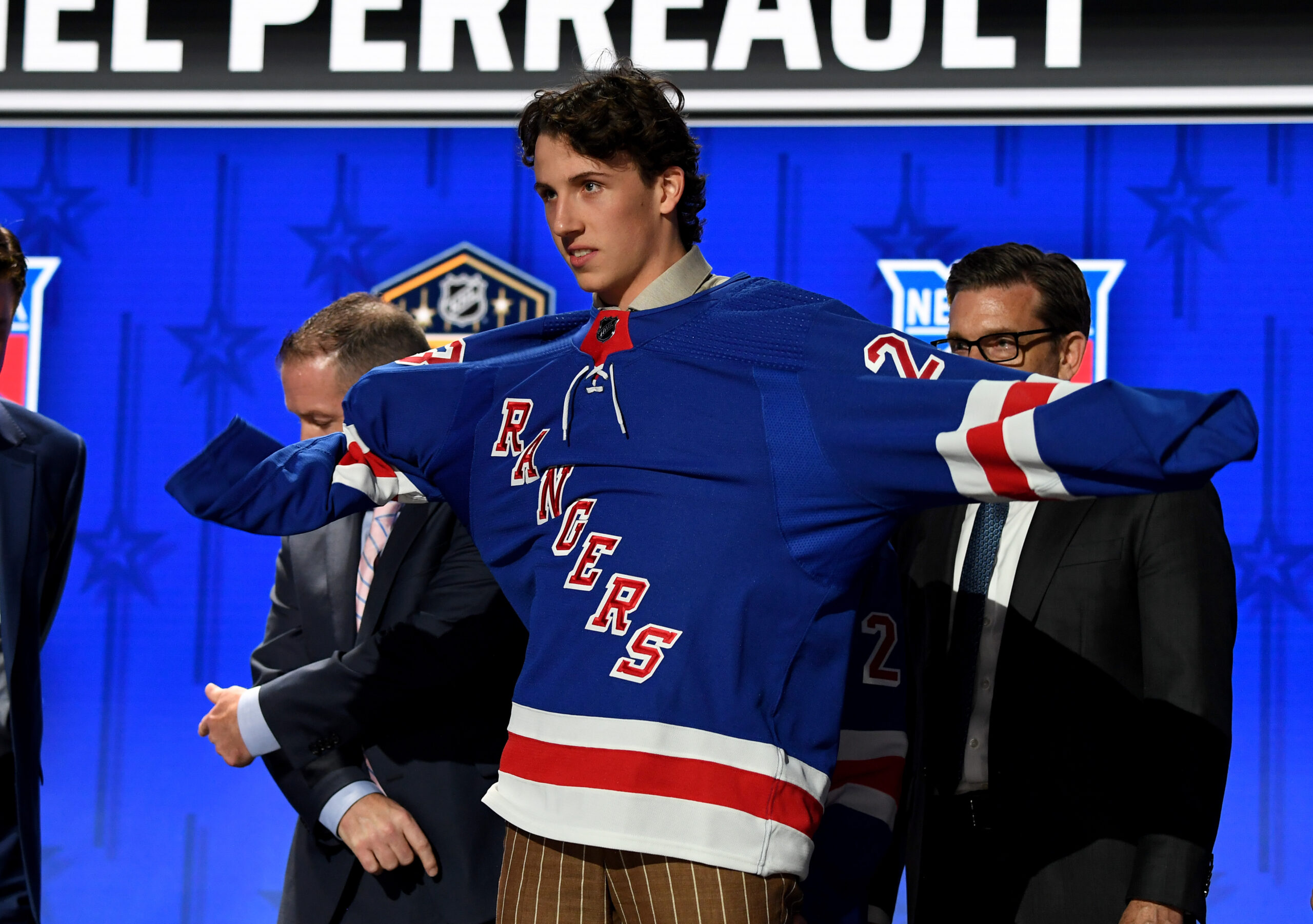 New York Rangers draft pick Gabriel Perreault puts on his sweater after being selected with the twenty third pick in round one of the 2023 NHL Draft at Bridgestone Arena