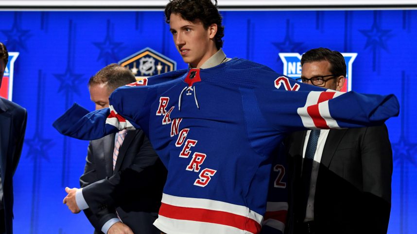 New York Rangers draft pick Gabriel Perreault puts on his sweater after being selected with the twenty third pick in round one of the 2023 NHL Draft at Bridgestone Arena