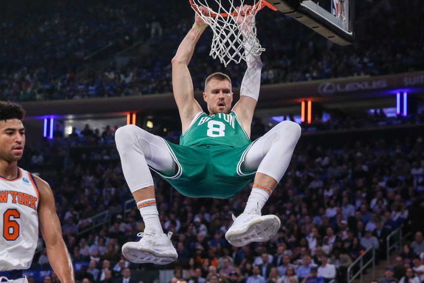 Boston Celtics center Kristaps Porzingis (8) hangs on the rim after a dunk in the first quarter against the New York Knicks at Madison Square Garden