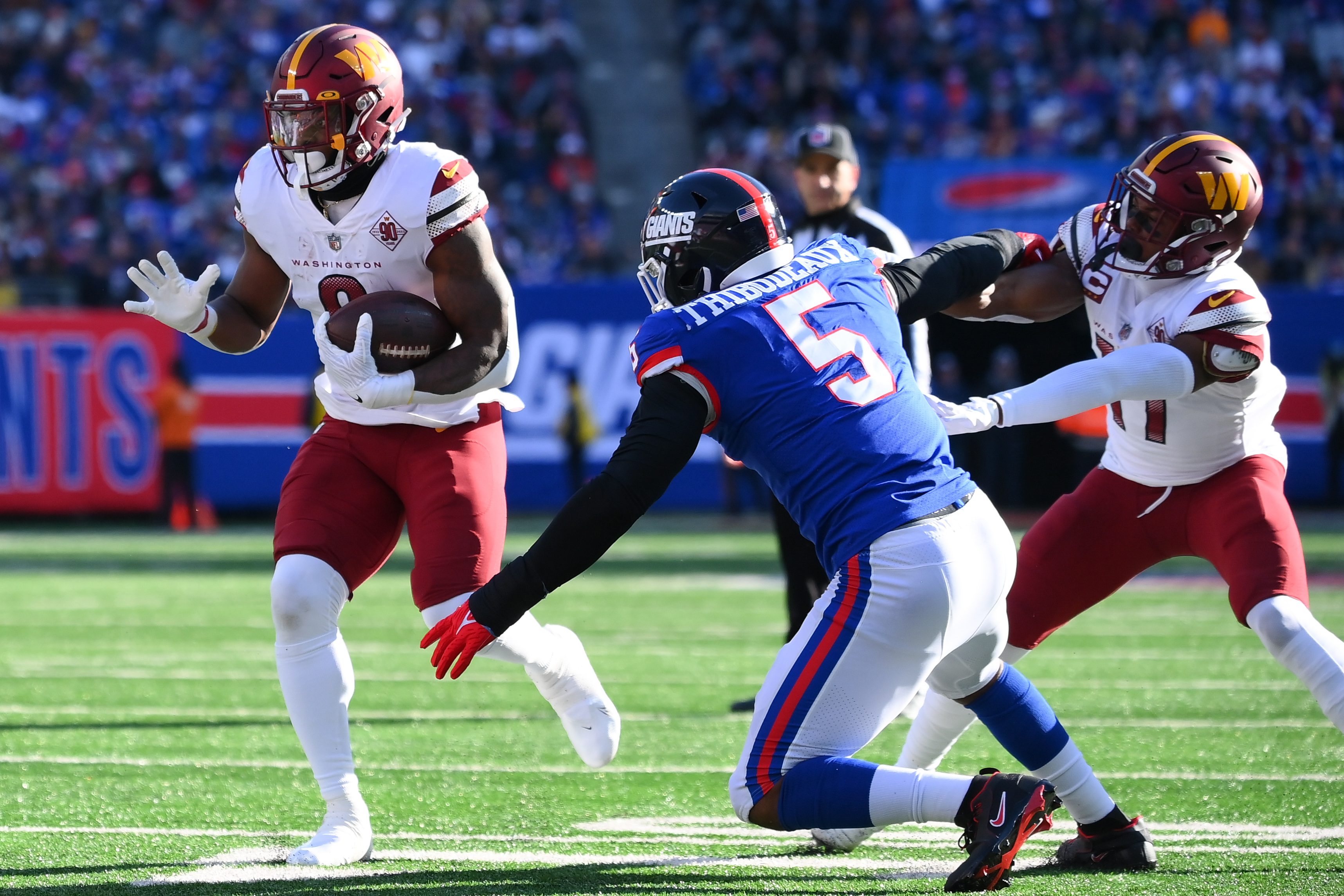 Washington Commanders running back Brian Robinson Jr. (8) runs as New York Giants defensive end Kayvon Thibodeaux (5) defends during the first half at MetLife Stadium