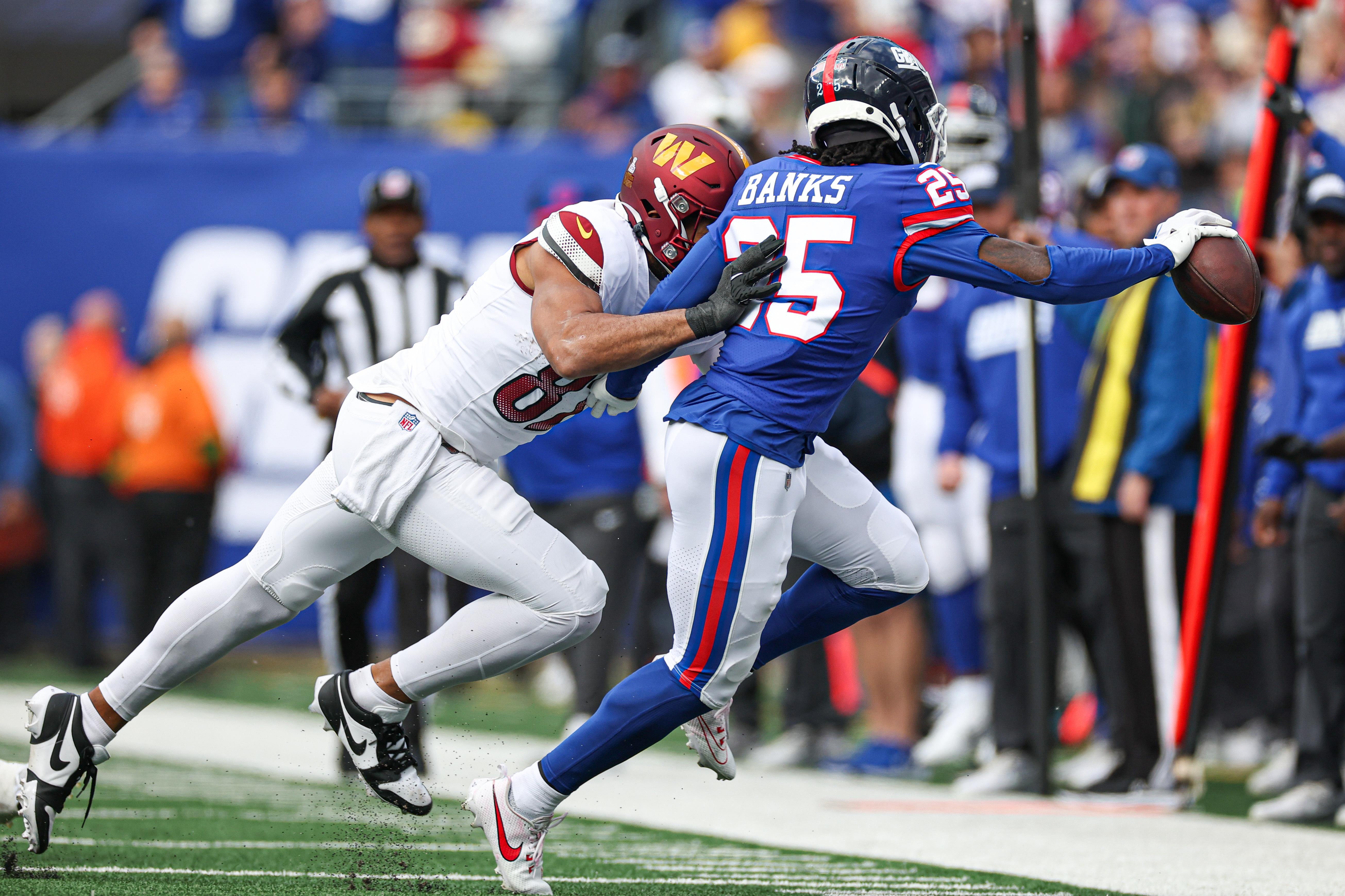 New York Giants cornerback Deonte Banks (25) is pushed out of bounds by Washington Commanders tight end Logan Thomas (82) after an interception during the first half at MetLife Stadium