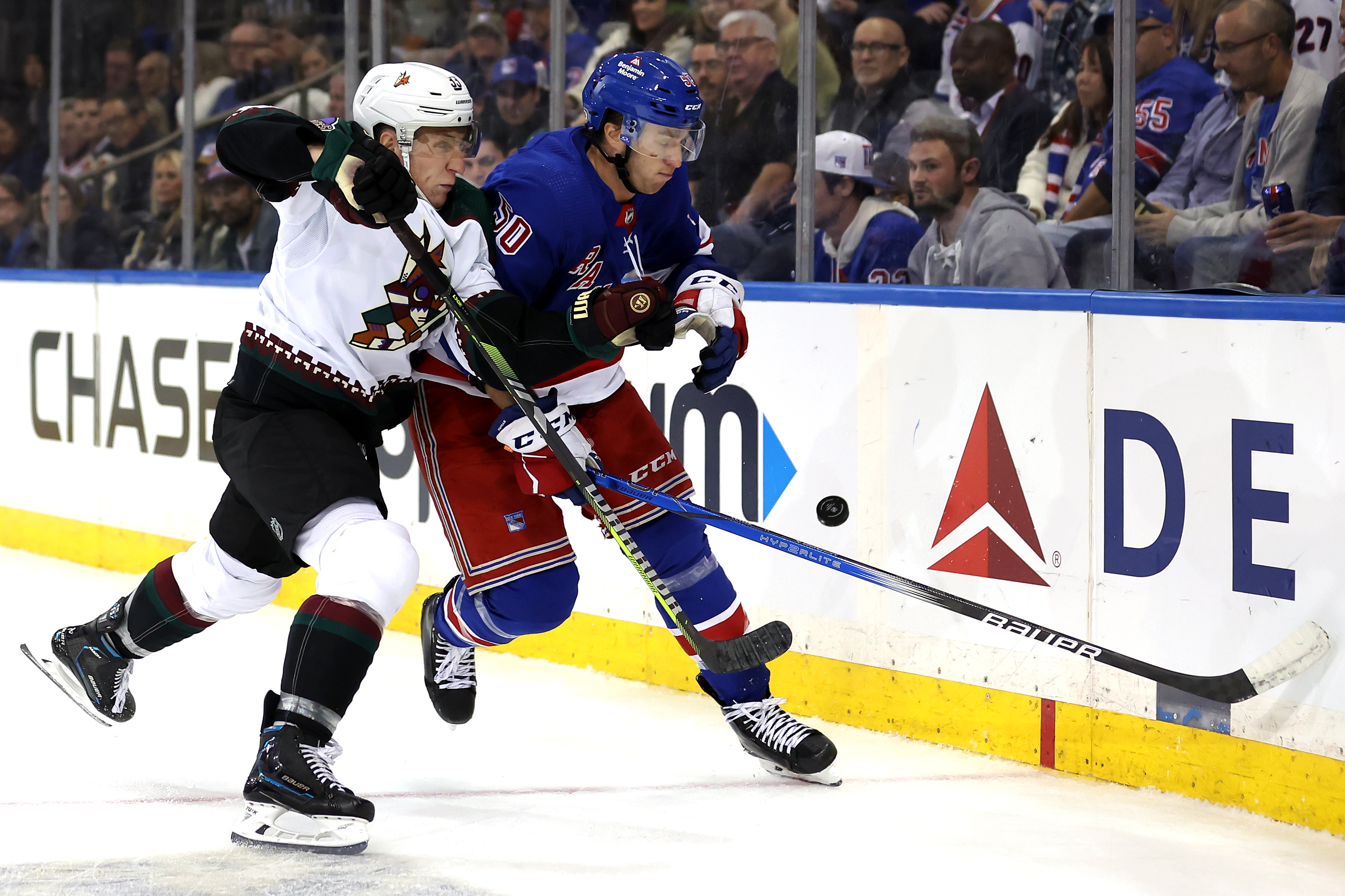 Arizona Coyotes defenseman Travis Dermott (33) and New York Rangers left wing Will Cuylle (50) fight for the puck during the second period at Madison Square Garden