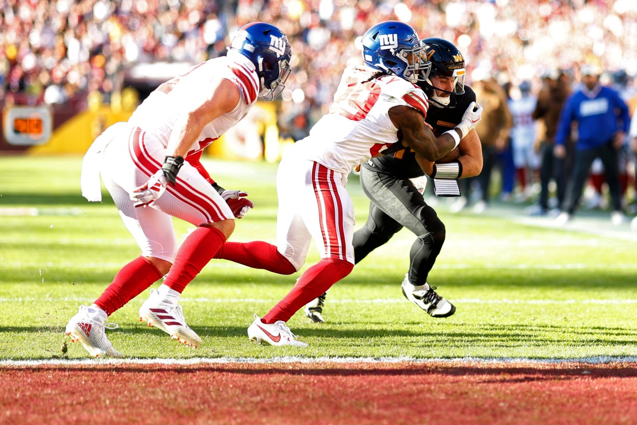 Washington Commanders quarterback Sam Howell (14) scores a touchdown as New York Giants safety Xavier McKinney (29) defends during the second quarter at FedExField