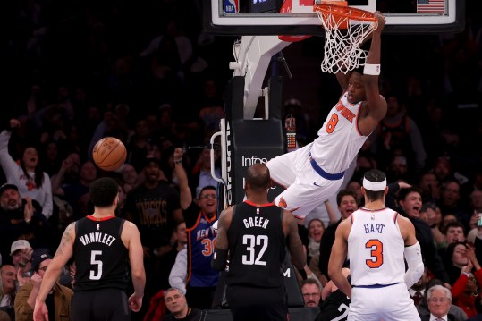 New York Knicks forward OG Anunoby (8) hangs on the rim after a dunk against Houston Rockets guard Fred VanVleet (5) and forward Jeff Green (32) during the fourth quarter at Madison Square Garden