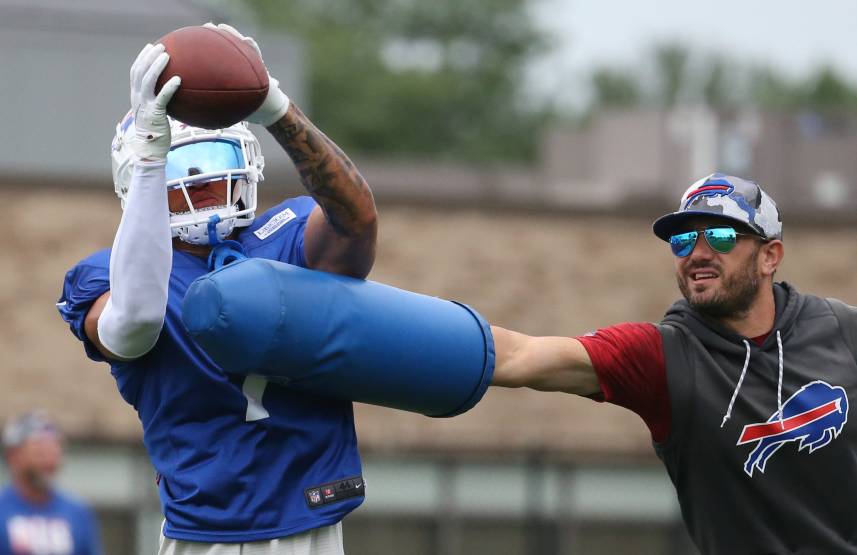Bills cornerback Taron Johnson (7) catches the ball as he is hit by linebackers coach Bobby Babich (New York Giants defensive coordinator candidate) during interception drills on day nine of Buffalo Bills training camp