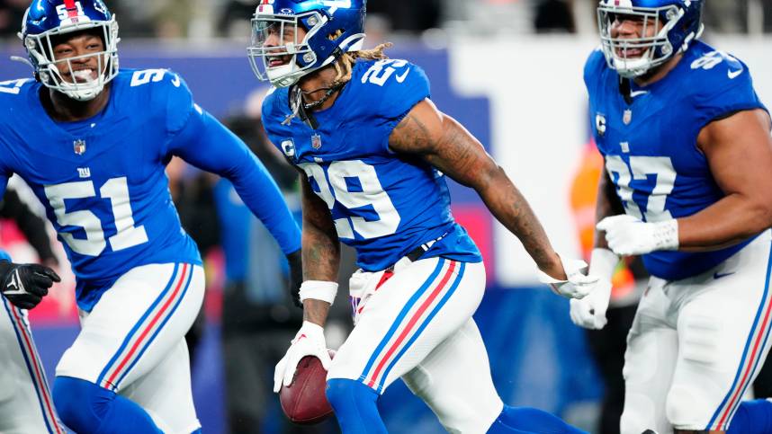 New York Giants safety Xavier McKinney (29) holds the ball as he celebrates with New York Giants linebacker Azeez Ojulari (51) and New York Giants defensive tackle Dexter Lawrence II (97) after he intercepted a Philadelphia Eagles pass