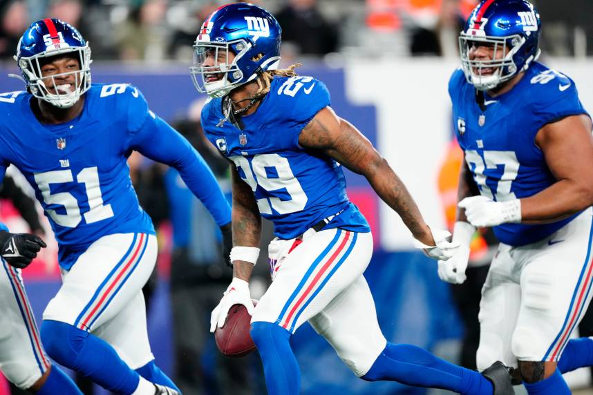 New York Giants safety Xavier McKinney (29) holds the ball as he celebrates with New York Giants linebacker Azeez Ojulari (51) and New York Giants defensive tackle Dexter Lawrence II (97) after he intercepted a Philadelphia Eagles pass