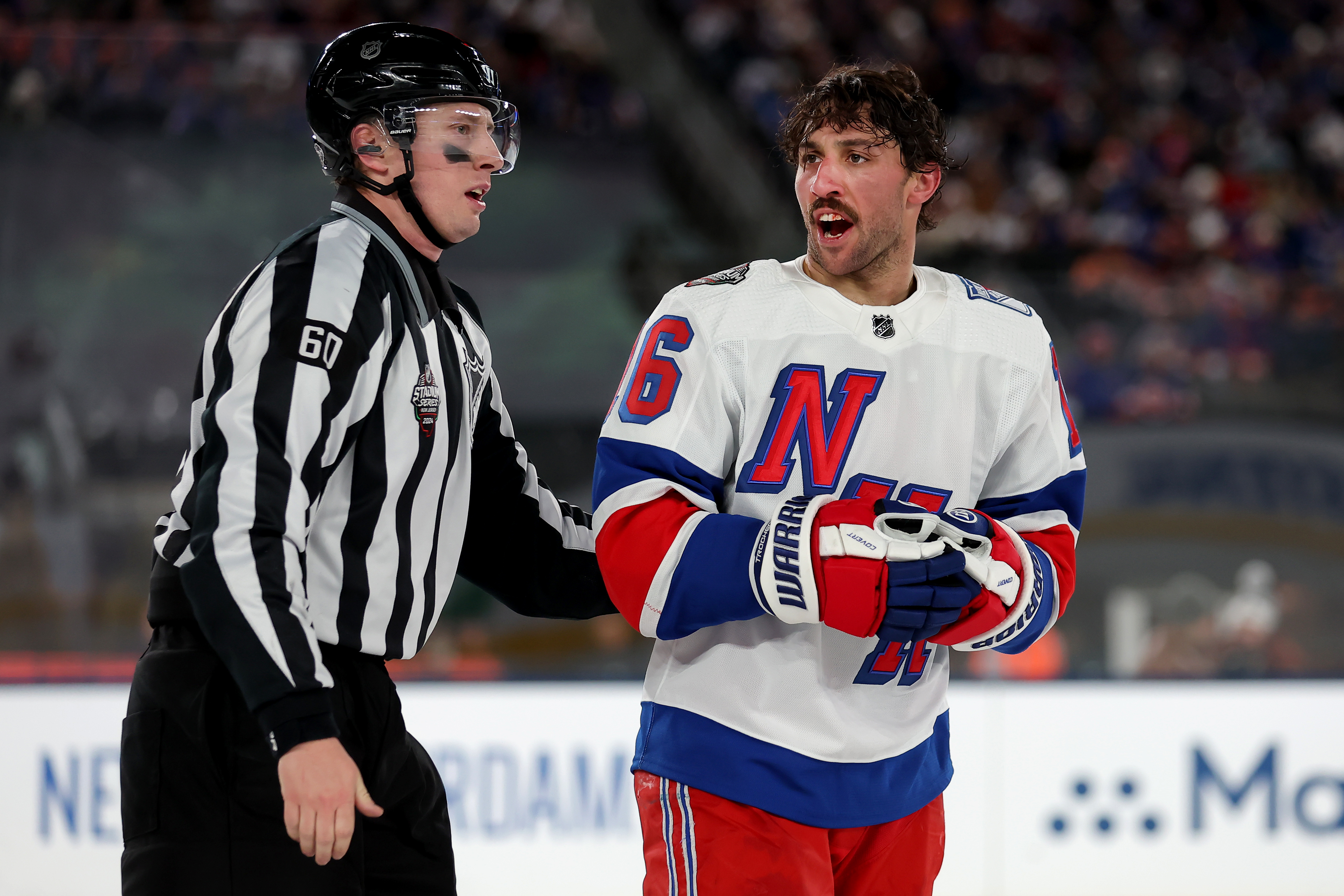 New York Rangers center Vincent Trocheck (16) is led off the ice by linesman Libor Suchanek (60) after a roughing call against Trochek and New York Islanders defenseman Alexander Romanov (not pictured) during the third period of a Stadium Series ice hockey game at MetLife Stadium