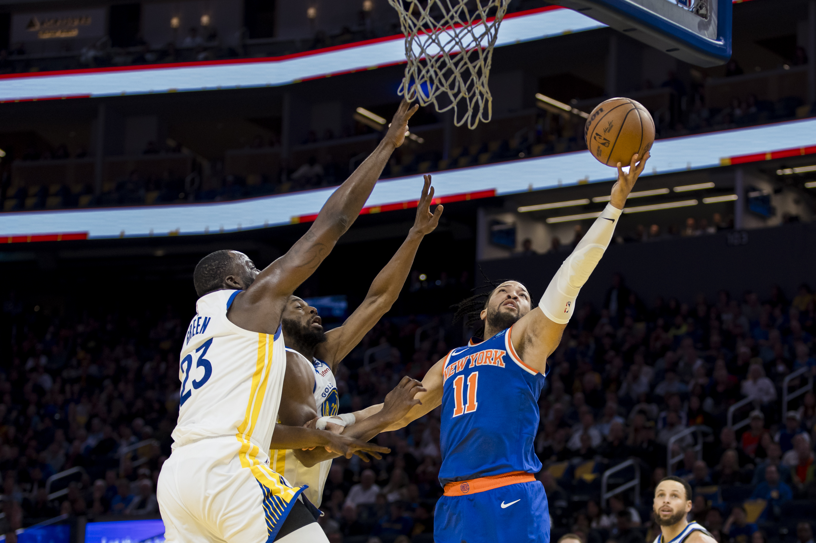 New York Knicks guard Jalen Brunson (11) shoots as Golden State Warriors center Draymond Green (23) and forward Andrew Wiggins (22) defend during the first half at Chase Center