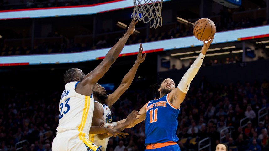 New York Knicks guard Jalen Brunson (11) shoots as Golden State Warriors center Draymond Green (23) and forward Andrew Wiggins (22) defend during the first half at Chase Center