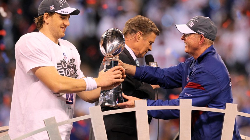 New York Giants head coach Tom Coughlin (right) hands the Vince Lombardi Trophy to quarterback Eli Manning (left) after Super Bowl XLVI against the New England Patriots at Lucas Oil Stadium