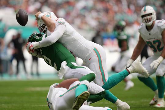 Miami Dolphins linebacker Bradley Chubb, top, and defensive tackle Christian Wilkins, bottom, hit New York Jets quarterback Zach Wilson (2) causing a fumble during the first half of an NFL game at Hard Rock Stadium in Miami Gardens, Dec. 17, 2023.