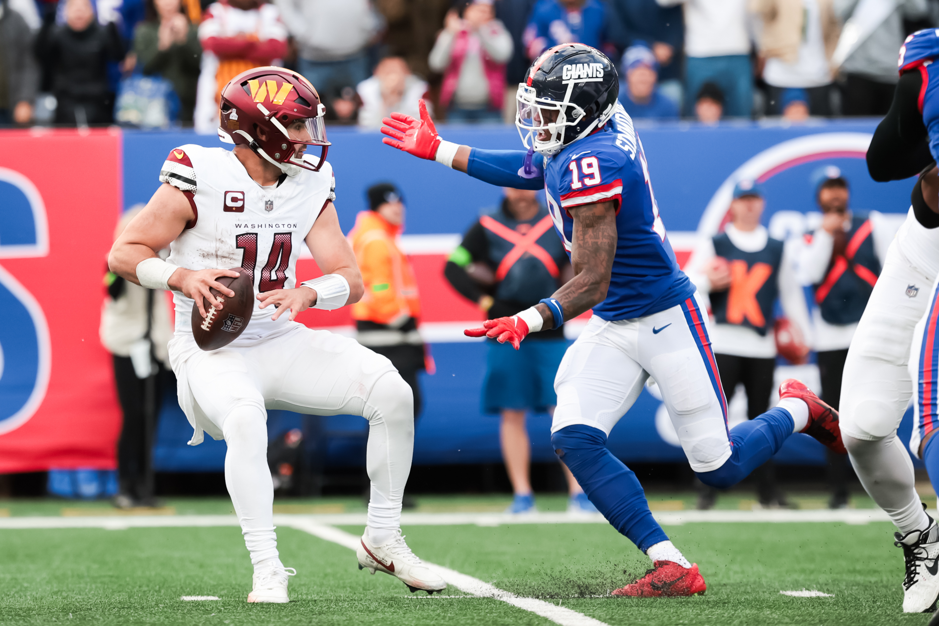 Oct 22, 2023; East Rutherford, New Jersey, USA; Washington Commanders quarterback Sam Howell (14) is pressured by New York Giants safety Isaiah Simmons (19) during the fourth quarter at MetLife Stadium. Mandatory Credit: Vincent Carchietta-USA TODAY Sports