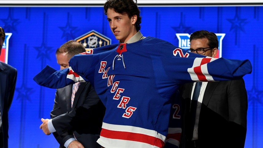 Jun 28, 2023; Nashville, Tennessee, USA; New York Rangers draft pick Gabriel Perreault puts on his sweater after being selected with the twenty third pick in round one of the 2023 NHL Draft at Bridgestone Arena. Mandatory Credit: Christopher Hanewinckel-USA TODAY Sports