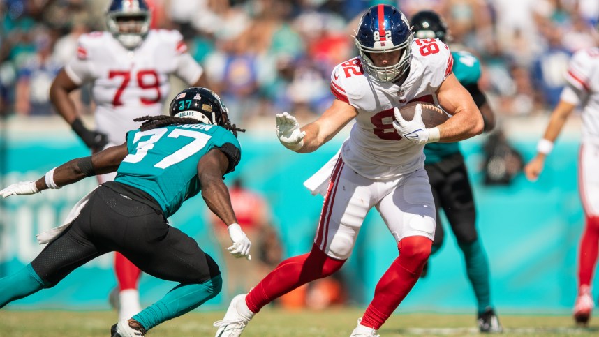 Oct 23, 2022; Jacksonville, Florida, USA;  New York Giants tight end Daniel Bellinger (82) catches the ball against Jacksonville Jaguars cornerback Tre Herndon (37) in the second quarter at TIAA Bank Field. Mandatory Credit: Jeremy Reper-USA TODAY Sports