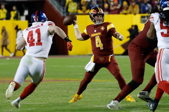 Dec 18, 2022; Landover, Maryland, USA; Washington Commanders quarterback Taylor Heinicke (4) throws a touchdown pass as New York Giants linebacker Micah McFadden (41) chases during the third quarter at FedExField. Mandatory Credit: Geoff Burke-USA TODAY Sports