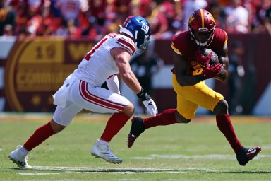 Sep 15, 2024; Landover, Maryland, USA; Washington Commanders running back Brian Robinson Jr. (8) runs the ball against New York Giants linebacker Micah McFadden (41) during the first quarter at Commanders Field. Mandatory Credit: Peter Casey-Imagn Images