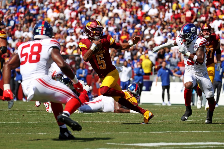 Sep 15, 2024; Landover, Maryland, USA; Washington Commanders quarterback Jayden Daniels (5) runs the ball against New York Giants safety Tyler Nubin (31) and linebacker Bobby Okereke (58) during the fourth quarter at Commanders Field. Mandatory Credit: Peter Casey-Imagn Images