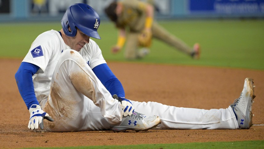 Sep 26, 2024; Los Angeles, California, USA;  Los Angeles Dodgers first baseman Freddie Freeman (5) grabs his ankle after he was injured during a play at first base in the seventh inning against the San Diego Padres at Dodger Stadium. Mandatory Credit: Jayne Kamin-Oncea-Imagn Images