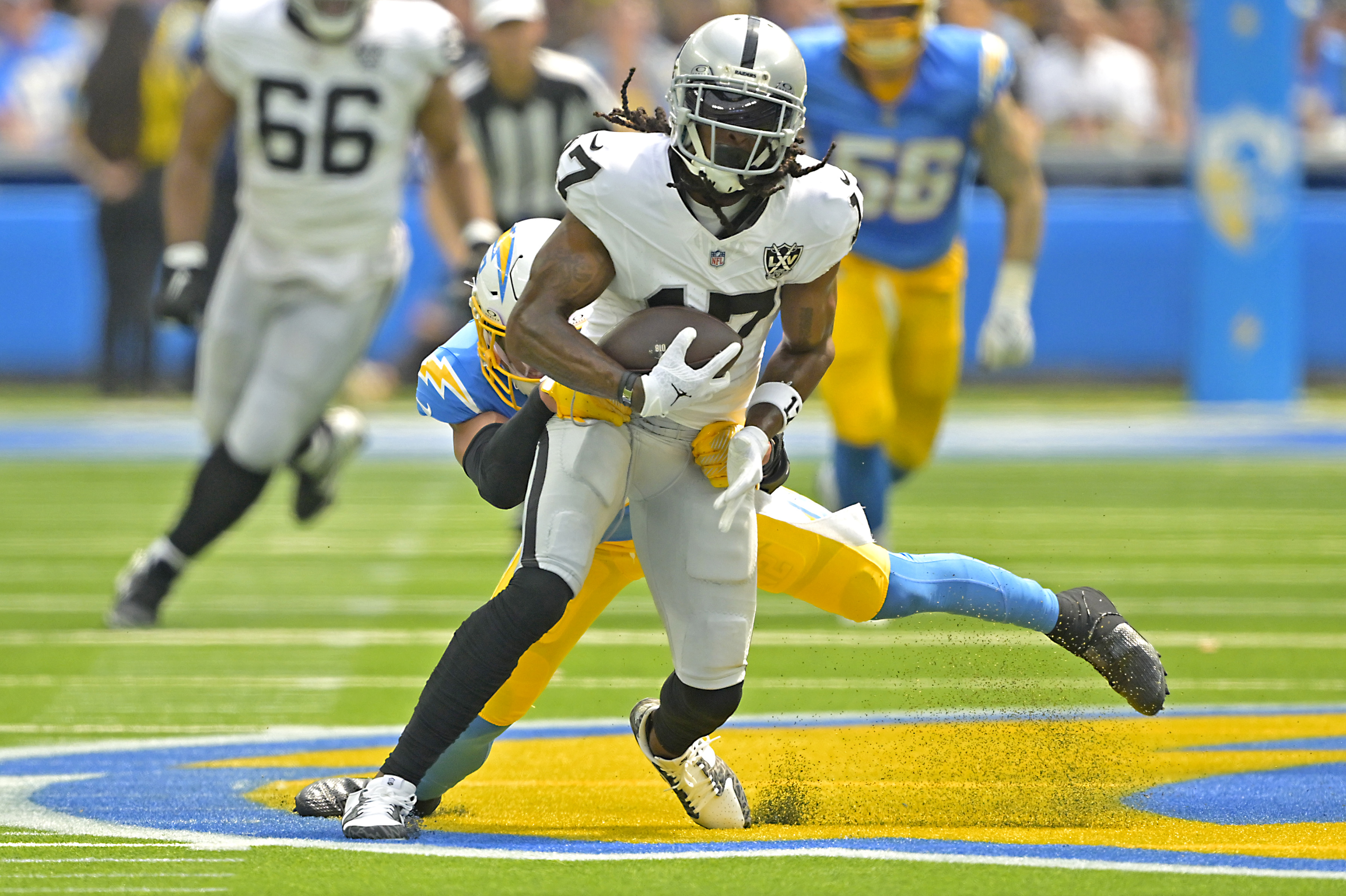 Sep 8, 2024; Inglewood, California, USA; Las Vegas Raiders wide receiver Davante Adams (17) is stopped by Los Angeles Chargers safety Alohi Gilman (32) after a compete pass in the first half at SoFi Stadium. Mandatory Credit: Jayne Kamin-Oncea-Imagn Images