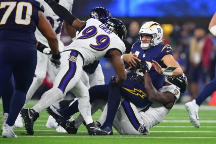 Nov 25, 2024; Inglewood, California, USA; Los Angeles Chargers quarterback Justin Herbert (10) is sacked by Baltimore Ravens cornerback Brandon Stephens (21) and linebacker Odafe Oweh (99) during the second half at SoFi Stadium. Mandatory Credit: Gary A. Vasquez-Imagn Images