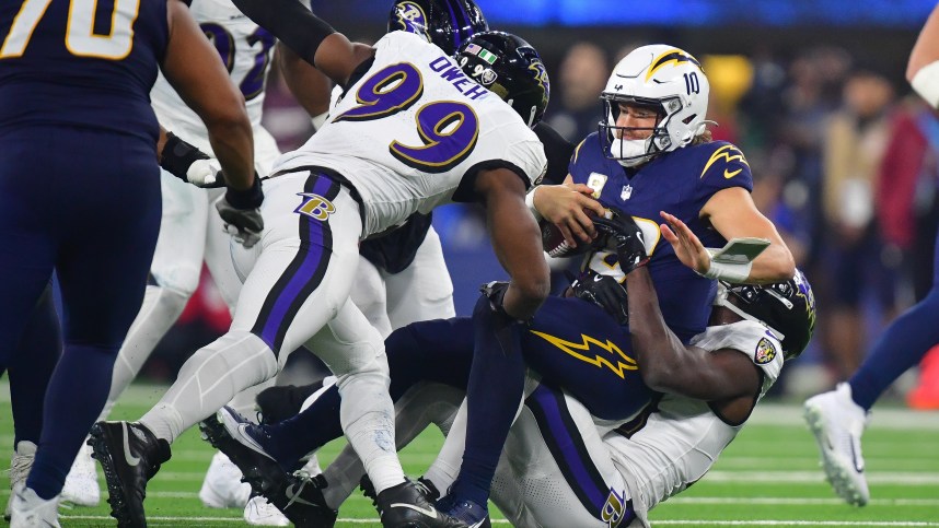 Nov 25, 2024; Inglewood, California, USA; Los Angeles Chargers quarterback Justin Herbert (10) is sacked by Baltimore Ravens cornerback Brandon Stephens (21) and linebacker Odafe Oweh (99) during the second half at SoFi Stadium. Mandatory Credit: Gary A. Vasquez-Imagn Images