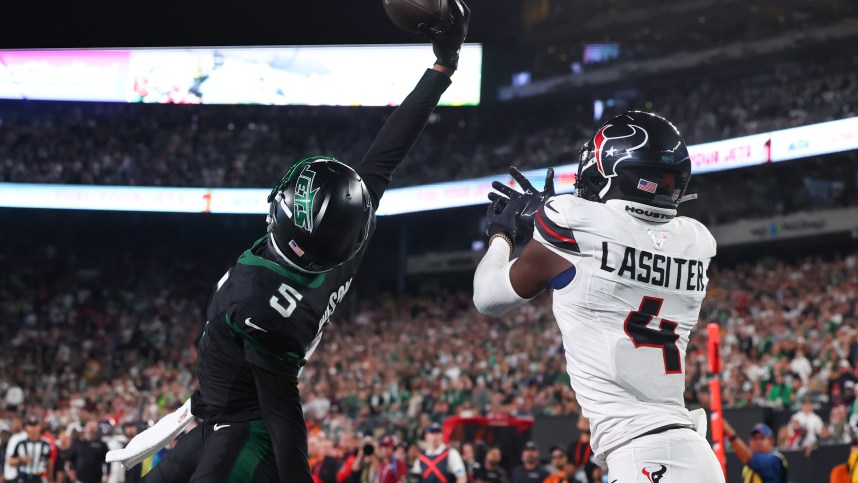 Oct 31, 2024; East Rutherford, New Jersey, USA; New York Jets wide receiver Garrett Wilson (5) catches a touchdown pass while being defended by Houston Texans cornerback Kamari Lassiter (4) during the second half at MetLife Stadium. Mandatory Credit: Ed Mulholland-Imagn Images