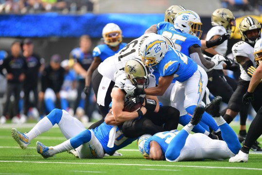 Oct 27, 2024; Inglewood, California, USA; New Orleans Saints tight end Taysom Hill (7) is brought down by Los Angeles Chargers linebacker Junior Colson (25) during the first half at SoFi Stadium. Mandatory Credit: Gary A. Vasquez-Imagn Images