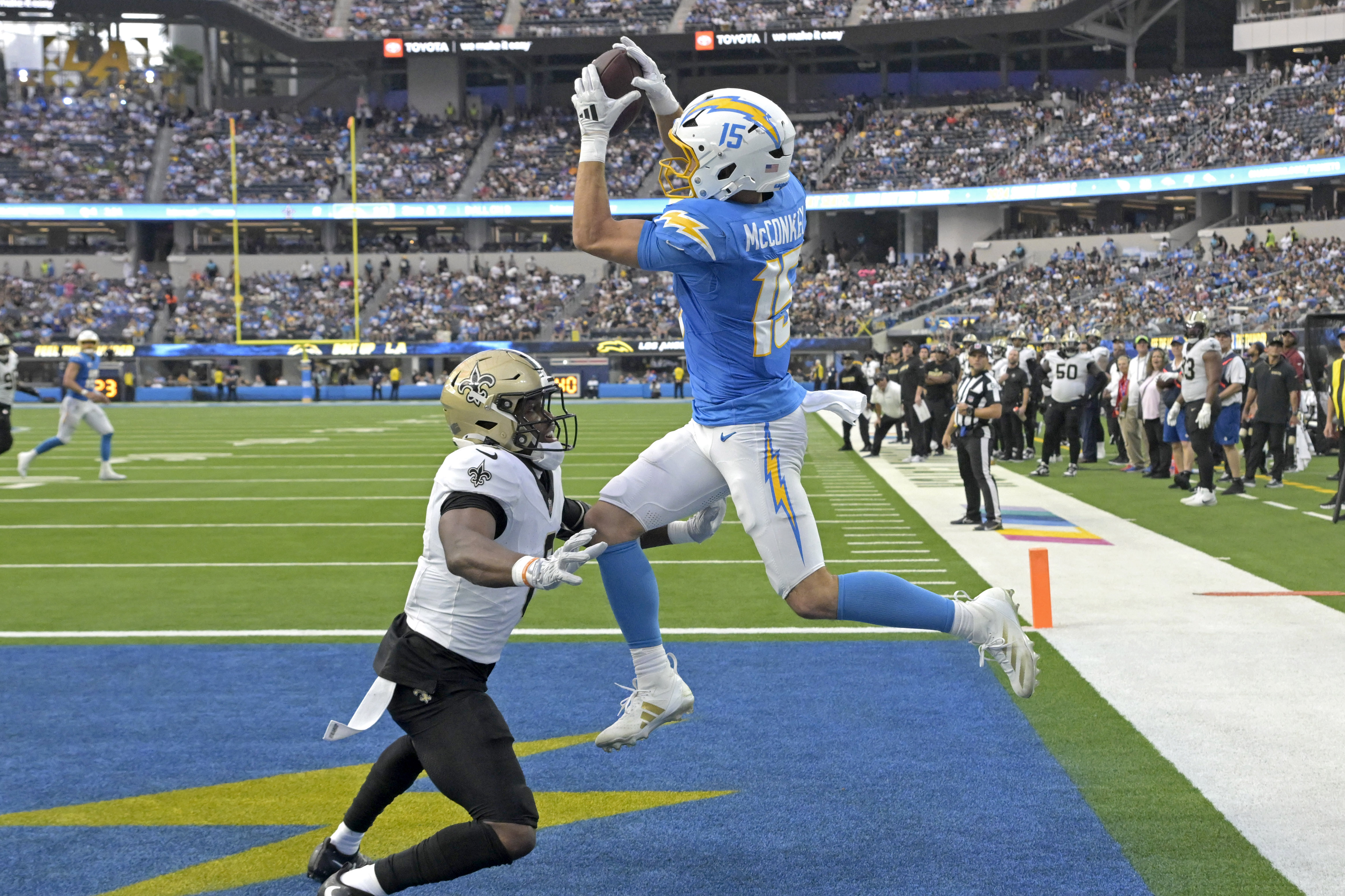 Oct 27, 2024; Inglewood, California, USA;  Los Angeles Chargers wide receiver Ladd McConkey (15) hangs on the the ball for a touchdown as he is defended by New Orleans Saints safety Ugo Amadi (0) in the second half at SoFi Stadium. Mandatory Credit: Jayne Kamin-Oncea-Imagn Images