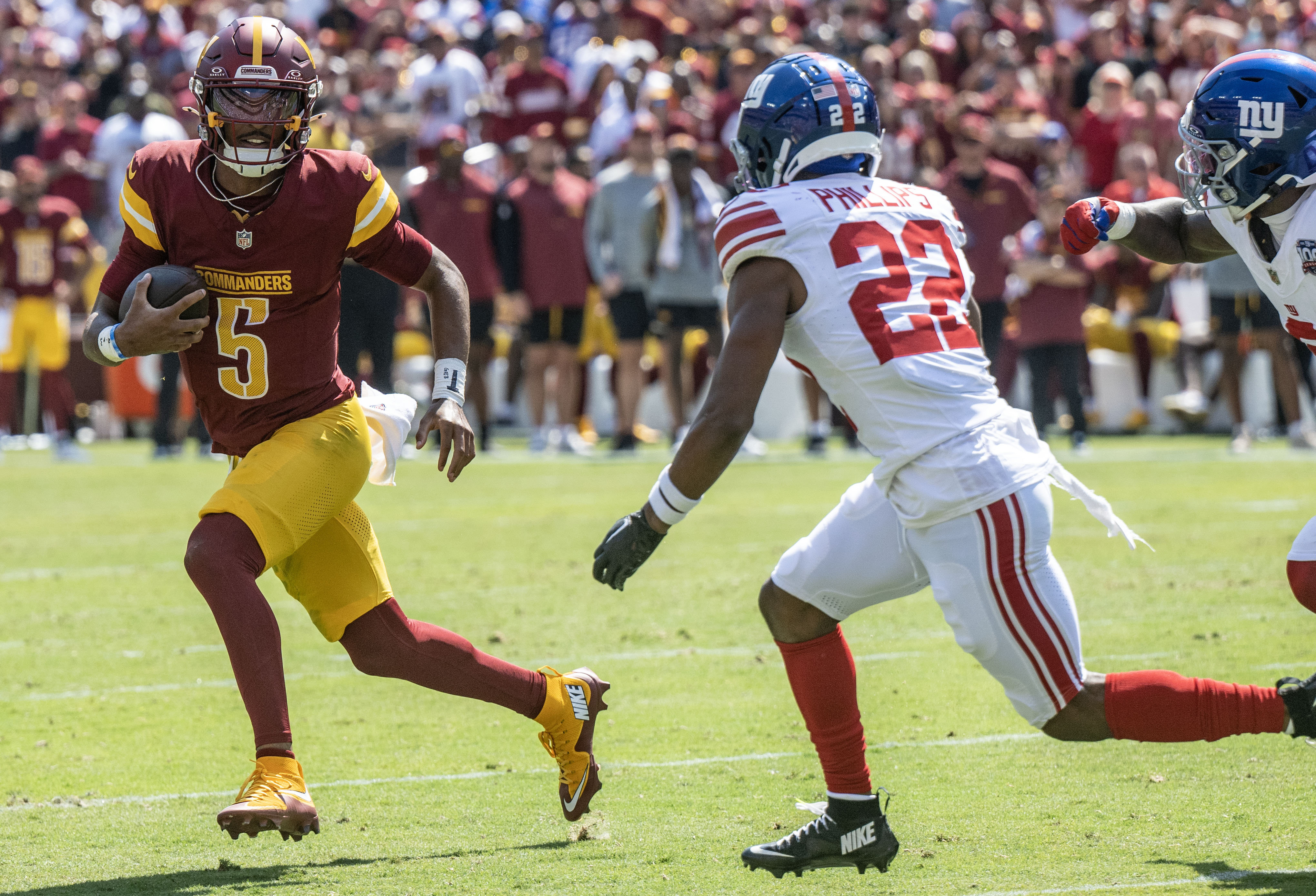 Sep 15, 2024; Landover, Maryland, USA; Washington Commanders quarterback Jayden Daniels (5) scrambles as New York Giants cornerback Dru Phillips (22) track him down during the first half at Commanders Field. Mandatory Credit: Luke Johnson-Imagn Images