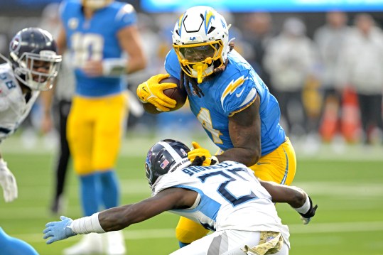 Nov 10, 2024; Inglewood, California, USA;  Los Angeles Chargers running back Gus Edwards (4) carries the ball for a first down before he is stopped by Tennessee Titans cornerback Jarvis Brownlee Jr. (29) in the first half at SoFi Stadium. Mandatory Credit: Jayne Kamin-Oncea-Imagn Images