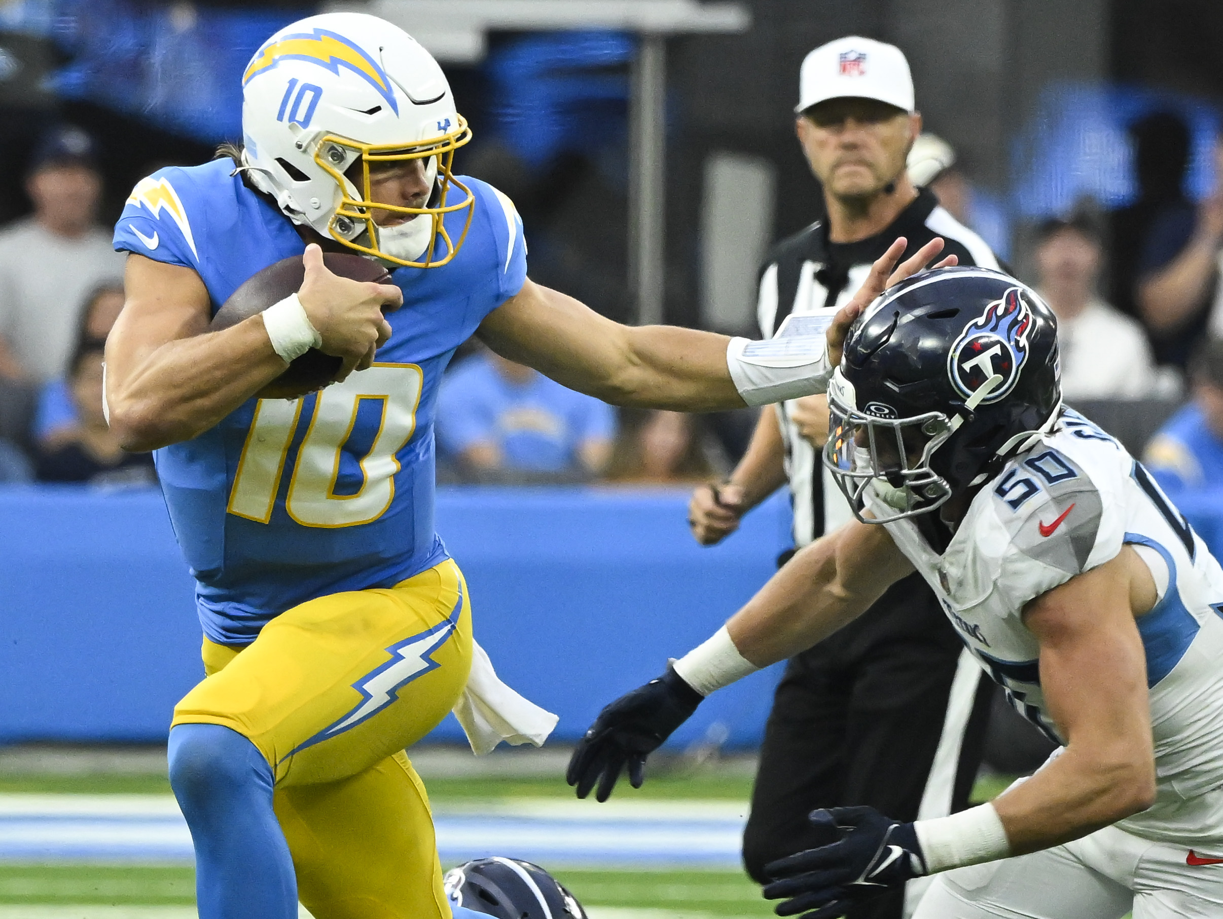 Nov 10, 2024; Inglewood, California, USA; Los Angeles Chargers quarterback Justin Herbert (10) stiff arms Tennessee Titans linebacker Jack Gibbens (50) during the second quarter at SoFi Stadium. Mandatory Credit: Robert Hanashiro-Imagn Images